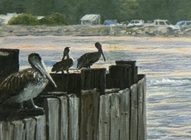 May include: An oil painting depicts three pelicans perched on weathered wooden pilings. The birds have brown and white plumage and long beaks. The background shows a beach scene with water, a shoreline, and a few buildings.