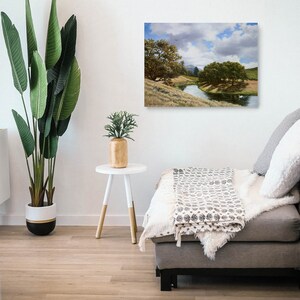 May include: A painting of a landscape with a river winding through a field of grass and trees. The sky is cloudy and blue.