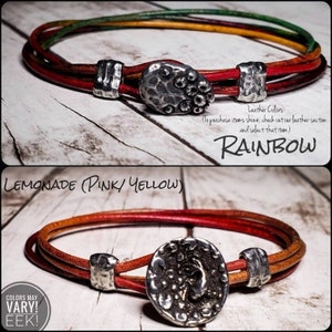 May include: Two leather bracelets with silver button closures. The top bracelet is rainbow colored and the bottom bracelet is red, orange, and yellow. The text "RAINBOW" and "LEMONADE (PINK/YELLOW)" is visible in the image. The text "COLORS MAY VARY! EEK!" is also visible in the image.