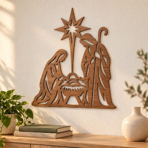 May include: A brown wooden wall art piece featuring a cutout nativity scene. The design depicts a figure kneeling beside a manger with a baby, a standing figure holding a staff, and a large eight-pointed star positioned above the central group.