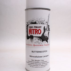 May include: A white spray can of Ohio Valley Nitro Custom Guitar Color Butterscotch Nitrocellulose Lacquer. The can has a black and white graphic of an electric guitar with the text "Ohio Valley Nitro" and "Custom Guitar Color". The can is 12 ounces.