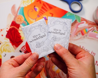 May include: Two white cards with black text and illustrations. The text on the cards reads "Alice in Wonderland".