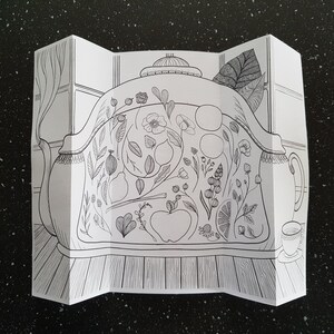 May include: A black and white line drawing of a teapot with a floral design. The teapot is on a table with a cup and saucer.