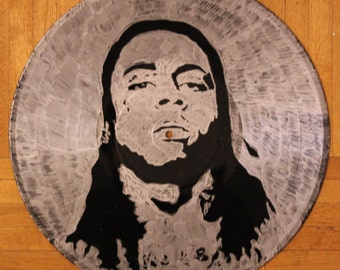May include: A black and white portrait of a person with long hair, painted on a silver vinyl record.