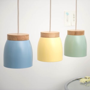 Puede incluir: Tres lámparas colgantes con tapas de madera y pantallas de vidrio de colores. Las pantallas son azul claro, amarillo y verde.