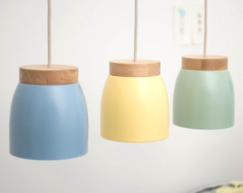 May include: Three pendant lights with wooden tops and coloured glass shades. The shades are light blue, yellow, and green.
