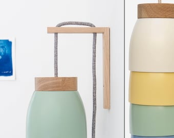Peut inclure: Un luminaire mural avec un cadre en bois et un abat-jour superposé vert, jaune, bleu et blanc. Le cordon est gris et l'abat-jour est en métal.