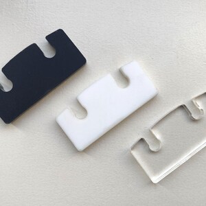 May include: Three plastic pieces with three cutouts each. The pieces are black, white, and clear.