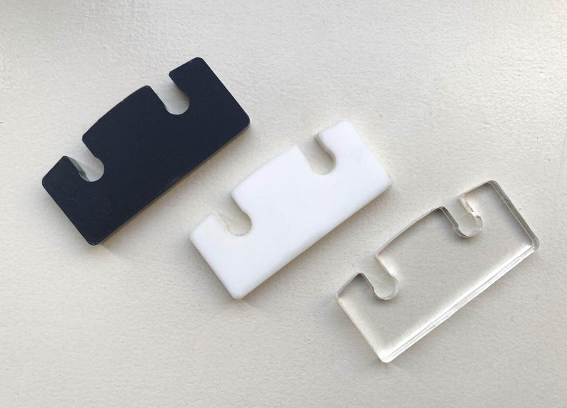 May include: Three plastic pieces with three cutouts each. The pieces are black, white, and clear.