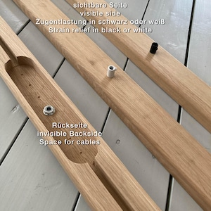 May include: Two wooden pieces for a furniture project. The top piece has the text "sichtbare Seite visible side Zugentlastung in schwarz oder wei&szlig; Strain relief in black or white". The bottom piece has the text "R&uuml;ckseite invisible Backside Space for cables".