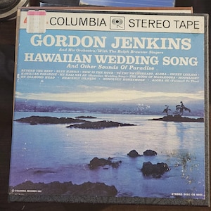 May include: Vintage Columbia Stereo Tape of Gordon Jenkins' "Hawaiian Wedding Song." The album cover features a serene ocean scene with islands and palm trees. The title and artist's name are in large, bold letters, with a list of song titles below.