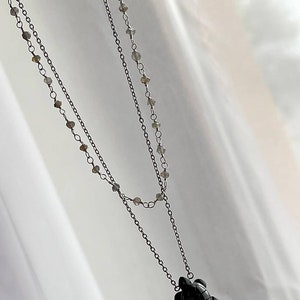 May include: A silver chain necklace with a black turtle pendant. The chain is made of small beads and is layered.