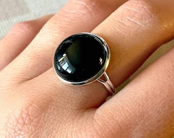Op de afbeelding: Een zilveren ring met een grote, ronde, zwarte onyxsteen.