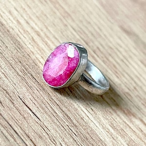 Può includere: Un anello d'argento con una grande pietra preziosa rosa di forma ovale incastonata in una montatura a  bezel.