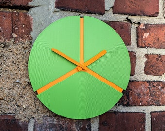 Orange-green round 3D-printed wall clock from biodegradable renewable plastic.