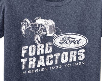 Puede incluir: Camiseta azul marino con un gráfico blanco desgastado de un tractor Ford y las palabras "FORD TRACTORS N SERIES 1939 TO 1952". Un logotipo circular con un caballo y las palabras "horse doodles" está en la parte inferior derecha.