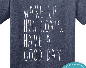 May include: A navy blue t-shirt with the text "WAKE UP. HUG GOATS. HAVE A GOOD DAY." in white. A circular logo with a white horse and the words "horse doodles" is on the bottom right.