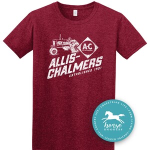 May include: Maroon t-shirt with a white graphic of a tractor and the text "ALLIS-CHALMERS ESTABLISHED 1901". A circular sticker with a horse graphic and the words "horse doodles" is on the bottom right.
