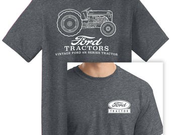 Puede incluir: Camiseta gris oscuro con un contorno blanco de un tractor Ford 8N vintage en la espalda. La camiseta también tiene el logotipo y el texto de Ford Tractor. Un logotipo más pequeño de Ford Tractor está en la parte delantera.