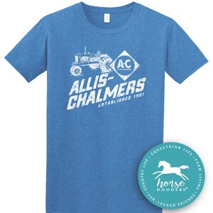 May include: Blue short-sleeved t-shirt with a distressed white graphic featuring a tractor, the text "ALLIS-CHALMERS ESTABLISHED 1901", and the "AC" logo. A round sticker with a horse graphic is on the bottom right.