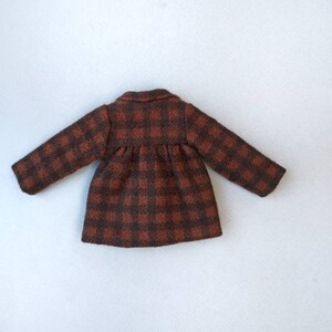 May include: A brown and black plaid coat with long sleeves and a button closure.