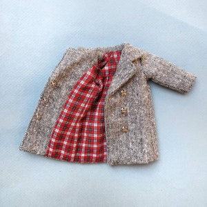 May include: A brown and black tweed coat with a red and white plaid lining. The coat has a double breasted closure with gold buttons.