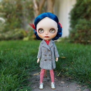 May include: A doll with blue hair, wearing a gray coat, red and white striped tights, and silver shoes. The doll has blue eyes and red lips.