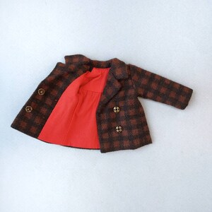 May include: A brown and black plaid coat with a red lining and gold buttons. The coat is open and the lining is visible.
