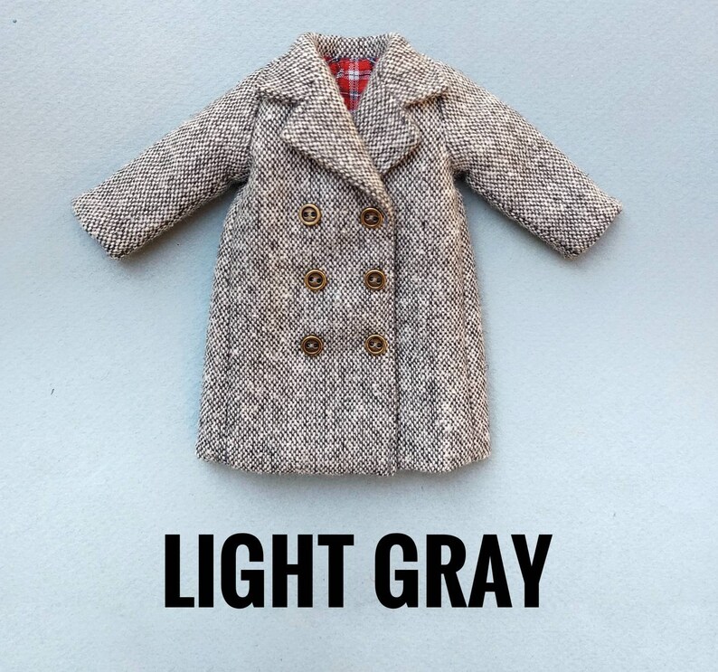 May include: A light gray double-breasted coat with a plaid lining. The coat has five gold buttons.