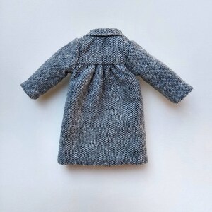 May include: A gray tweed coat with a long, fitted silhouette and long sleeves.