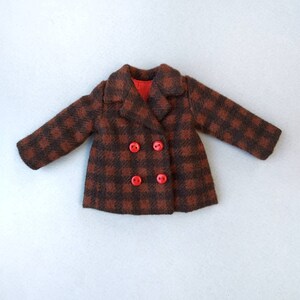 May include: A brown and black plaid coat with red buttons. The coat has a double breasted closure and a collar.
