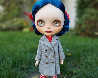May include: A doll with blue hair, wearing a gray coat with a double breasted closure, red and white striped leggings, and red and white bows in her hair.