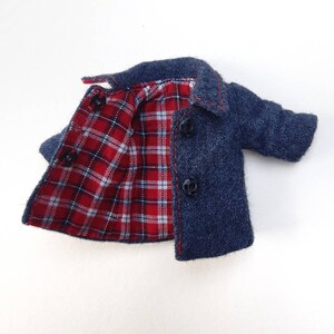 May include: A blue denim jacket with a red and white checked lining. The jacket has a button fastening and two pockets.