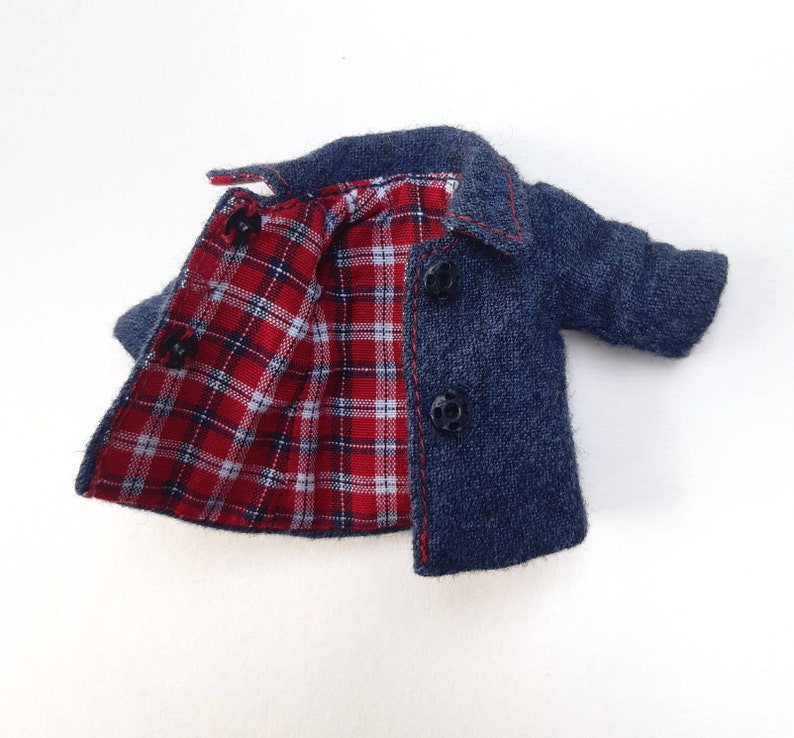 May include: A blue denim jacket with a red and white checked lining. The jacket has a button fastening and two pockets.
