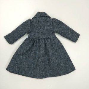 Puede incluir: Un abrigo gris con estampado de espiga, falda larga y fluida y mangas largas.