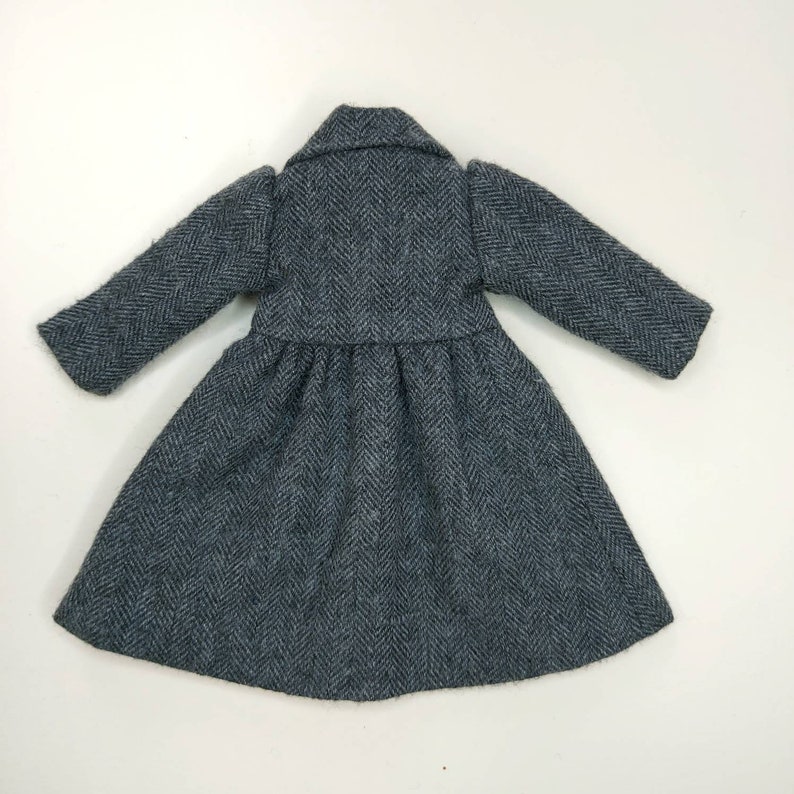 Puede incluir: Un abrigo gris con estampado de espiga, falda larga y fluida y mangas largas.