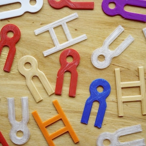 May include: A collection of colorful plastic shapes, including ladders and figures with holes, arranged on a wooden surface.