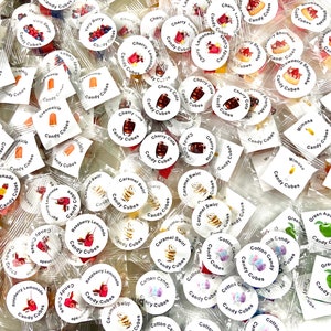 May include: A variety of small, clear plastic bags filled with colorful candy cubes. Each bag has a round sticker with a different flavor and image, such as cherry cola, strawberry lemonade, and caramel swirl.