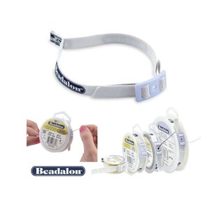 May include: White Beadalon beading thread spool holder with a white elastic strap and a blue plastic buckle. The strap is labeled "Beadalon".