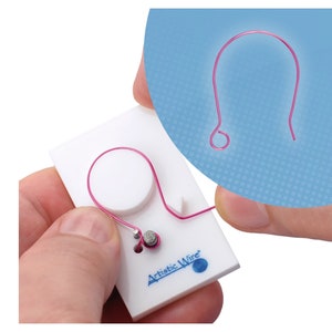 Pode incluir: Uma ferramenta de plástico branco com um pequeno furo redondo e um furo redondo maior. Um fio rosa está sendo dobrado em forma de laço usando a ferramenta. A ferramenta é etiquetada como "Artistic Wire".