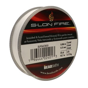 Könnte beinhalten: Eine Spule weißen S-LON FIRE geflochtenen und verschmolzenen Perlenfadens. Das Etikett lautet "braided & fused bead thread/fil à perles tressé et fusionné/hilo trenzado y fusionado para cuentas" und listet die Fadengröße als 0,006 Zoll (0,15 mm) und die Spulengröße als 50 Yards (45,7 m) und 6 Pfund (2,72 kg) auf.
