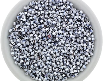 May include: A bowl filled with silver-toned faceted glass beads. The beads are small and have a shiny, reflective surface.