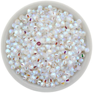May include: A bowl filled with iridescent white crystal beads. The beads are faceted and have a rainbow sheen.