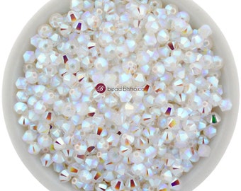 May include: A bowl filled with iridescent white crystal beads. The beads are faceted and have a rainbow sheen.