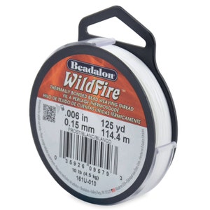 May include: A spool of white Beadalon WildFire thermally bonded bead weaving thread. The spool is labeled with the text "0.006 in 125 yd 0.15 mm 114.4 m FROST/BLANC/BLANCO 10 lb (4.5 kg) 161U-010".