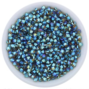 May include: A bowl filled with teal blue iridescent glass beads. The beads are small and have a faceted shape.
