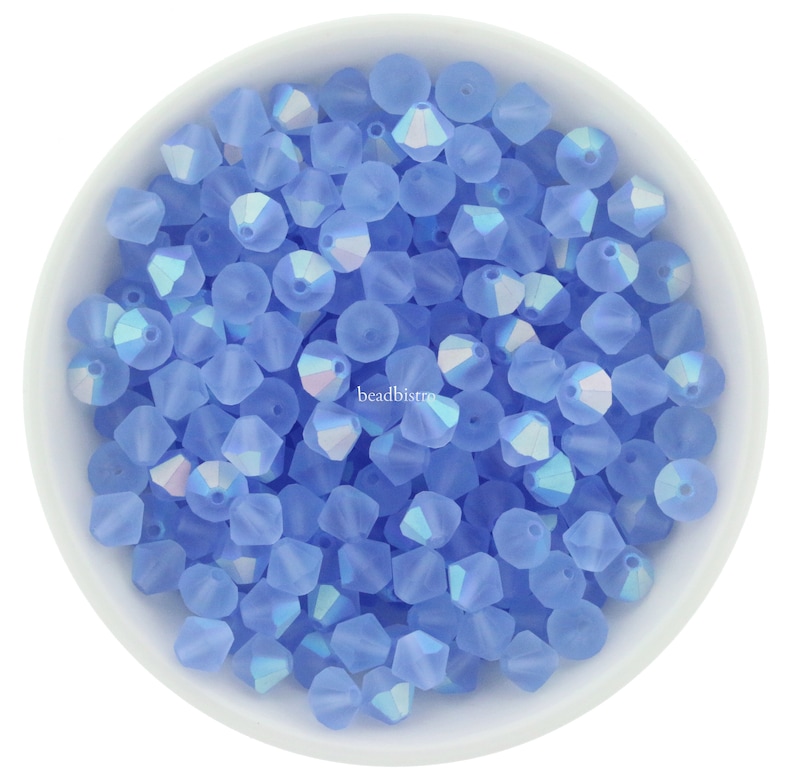 K&ouml;nnte beinhalten: Eine Schale gef&uuml;llt mit hellblauen, irisierenden Glasperlen. Die Perlen sind facettiert und haben eine matte Oberfl&auml;che.