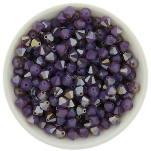 Puede incluir: Un bol de cuentas de cristal morado con forma puntiaguda facetada. Las cuentas tienen un acabado iridiscente.