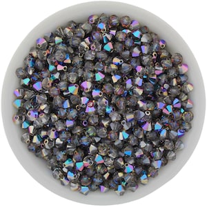 May include: A bowl filled with iridescent, faceted, dark gray glass beads. The beads have a rainbow sheen.