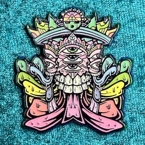 May include: A colorful enamel pin featuring a stylized, multi-eyed creature with a crown. The pin has a detailed design with pink, yellow, green, and blue accents, and a shiny, metallic border. The overall theme is psychedelic and artistic.